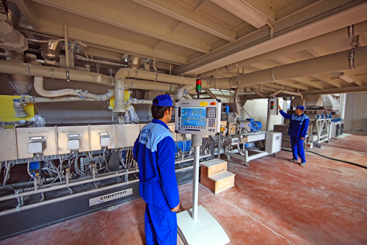 Workers operating control panel on production line